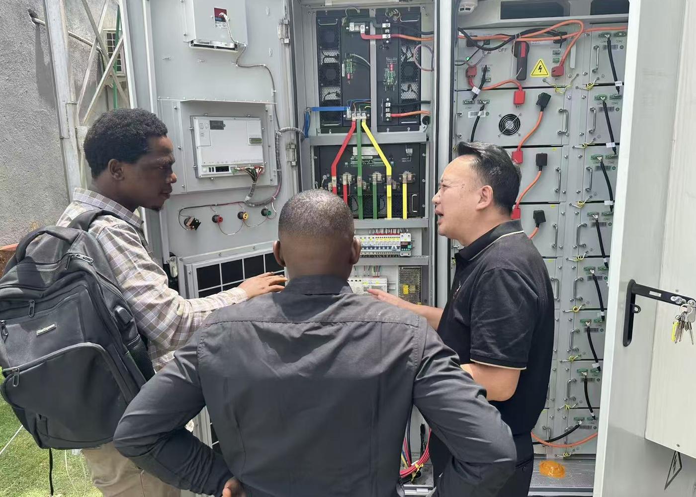 Engineer training local technicians at a battery storage cabinet